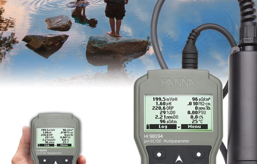 A light blue Hanna Instruments HI83300 Multiparameter Photometer on a white background. The laboratory device features a main console with a digital display and keypad, alongside a built-in articulated arm that suspends a sensor probe into a glass beaker filled with clear liquid.